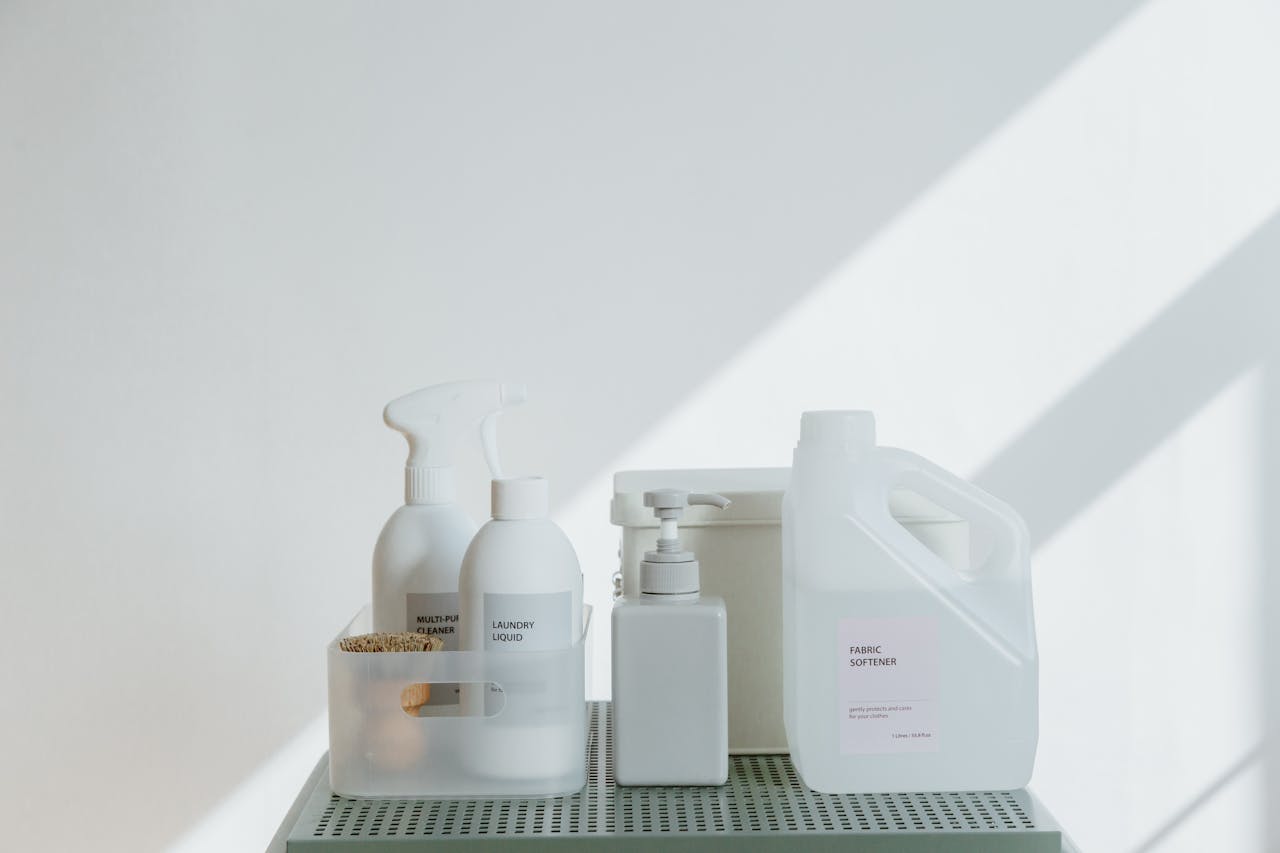 Clean and simple display of various cleaning products in soft lighting on a white background.